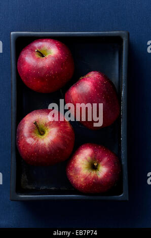 Ripe red apples in a box over blue cloth, above view Stock Photo