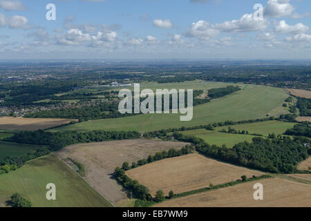 An aerial view of the Epsom Downs with the racecourse visible and the tall buildings of London in the distance