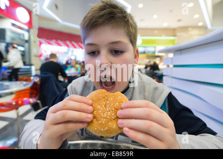 Teen boy eats  hamburger n Cafe Stock Photo