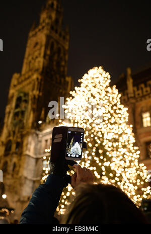 Munich, Germany. 27th Nov, 2014. A visitor takes a picture of an gigantic Christmas tree at the Christmas Market in Munich, Germany, 27 November 2014. Photo: Andreas Gebert/dpa/Alamy Live News Stock Photo