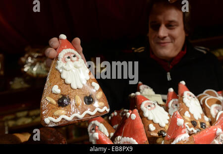 Munich, Germany. 27th Nov, 2014. A salesman shows his gingerbred Santa Claus at the Christmas Market in Munich, Germany, 27 November 2014. Photo: Andreas Gebert/dpa/Alamy Live News Stock Photo