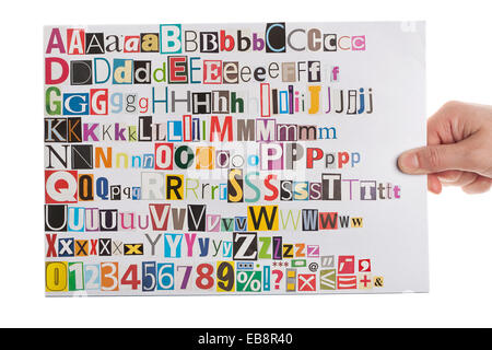 Hand holding newspaper clippings alphabet with letters, numbers and symbols, isolated on white background. Stock Photo