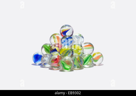 A stacked pyramid of coloured (or colored) glass marbles on a white background Stock Photo