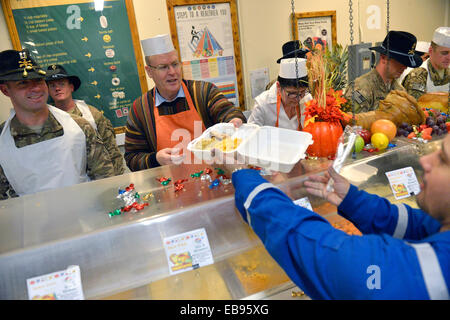 US Deputy Secretary of Defense Bob Work (center) serves sliced turkey to troops waiting in line for Thanksgiving lunch at Forward Operating Base Fenty  November 27, 2014 in Jalalabad, Afghanistan. Work visited Afghanistan to thank service men and women for their service during the holidays. Stock Photo