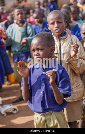Students at a primary school in Northern Tanzania stand in line at the end of the school day ceremony and clap to music. Stock Photo