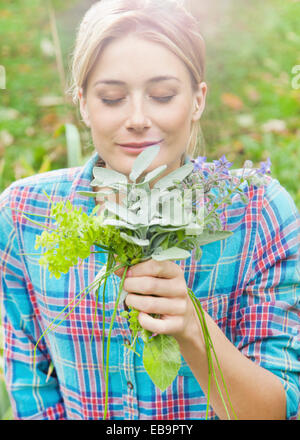 Woman in Garden Smelling a Bunch of Herbs and Flowers