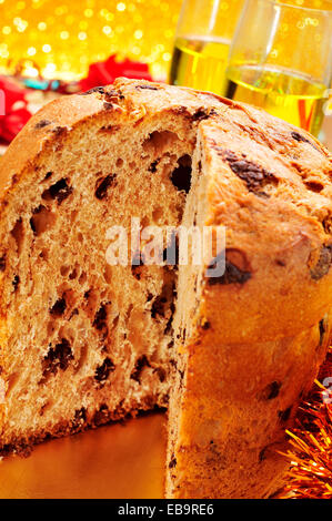 closeup of a panettone, a typical Italian sweet for Christmas time, on a set table with some glasses with champagne in the backg Stock Photo