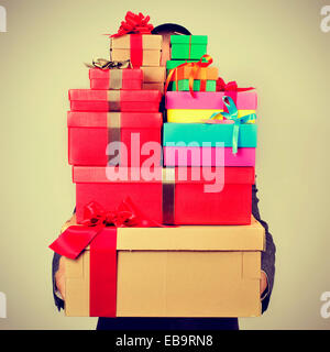a young man in suit carrying a pile of gift boxes of different colors, with a filter effect Stock Photo