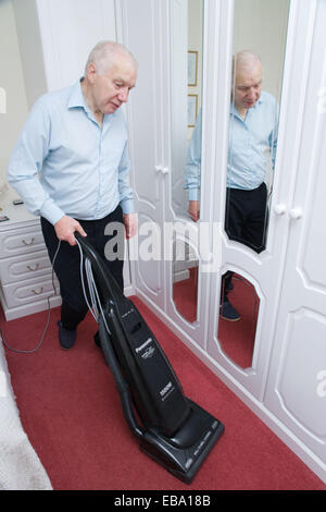 Older man hoovering in the bedroom, Stock Photo