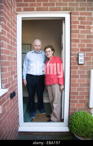 Older couple standing outside their front door together, Stock Photo