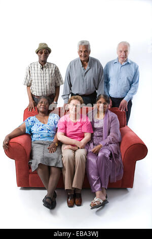 Multiracial group of older people sitting on a sofa together smiling, Stock Photo
