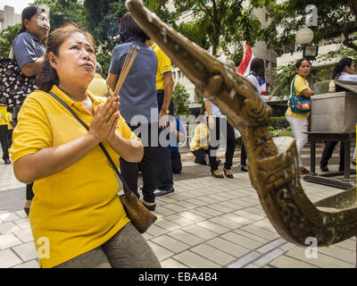 Bangkok, Bangkok, Thailand. 28th Nov, 2014. A woman on the plaza in front of Siriraj Hospital prays for Bhumibol Adulyadej, the King of Thailand. The King was born on December 5, 1927, in Cambridge, Massachusetts. The family was in the United States because his father, Prince Mahidol, was studying Public Health at Harvard University. He has reigned since 1946 and is the world's currently reigning longest serving monarch and the longest serving monarch in Thai history. Bhumibol, who is in poor health, is revered by the Thai people. His birthday is a national holiday and is also celebrated as Stock Photo