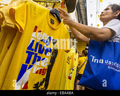 Bangkok, Bangkok, Thailand. 28th Nov, 2014. A woman in Bangkok looks at tee shirts that say ''Long Live the King'' before the King's Birthday in Thailand. Bhumibol Adulyadej, the King of Thailand, was born on December 5, 1927, in Cambridge, Massachusetts. The family was in the United States because his father, Prince Mahidol, was studying Public Health at Harvard University. He has reigned since 1946 and is the world's currently reigning longest serving monarch and the longest serving monarch in Thai history. Bhumibol, who is in poor health, is revered by the Thai people. His birthday is a Stock Photo