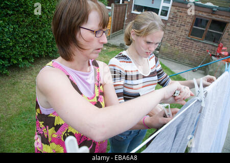 Teenage girl helping her mother hang out the washing, Stock Photo