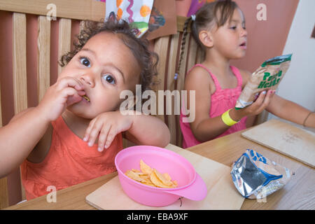 Two sisters sitting at the dinner table having a snack, Stock Photo