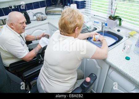 Disabled couple doing the washing up together in their nonadapted kitchen, Stock Photo