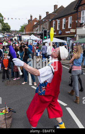 Brightly dressed clown juggles clubs for crowds at the Haslemere Charter Fair. Stock Photo