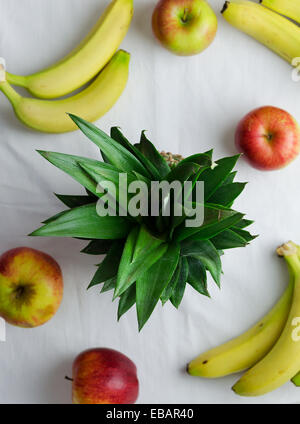 Pineapple, apples and bananas over white cloth, above view Stock Photo