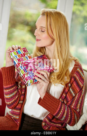 Happy woman sat with birthday presents Stock Photo