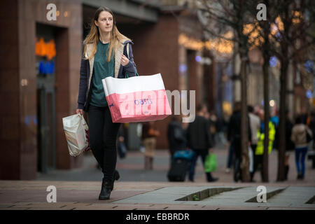 Glasgow, Scotland, UK. 28th November, 2014. A woman carries bags of shopping on Buchanan Street during 'Black Friday' sales on November 28, 2014  in Glasgow,Scotland. Originating in the USA as a sales day that following the Thanksgiving holiday, 'Black Friday' is becoming an increasingly popular shopping day in the UK Credit:  Sam Kovak/Alamy Live News Stock Photo