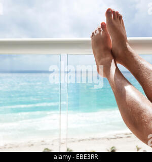 Male legs in hotel balcony over sea view, travel destination concept Stock Photo