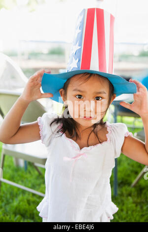 Portrait of young girl outdoors, wearing American, patriotic construction paper hat, Independence Day, USA Stock Photo