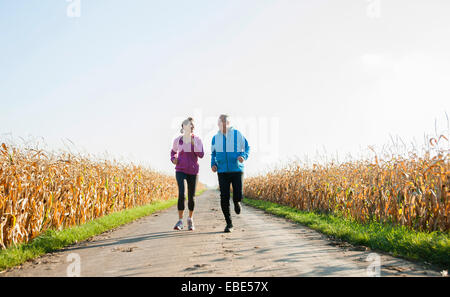 Adult couple running on country road, Germany Stock Photo