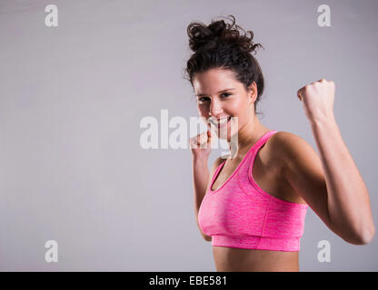 Close-up portrait of teenage girl exercising, smiling and looking at camera, studio shot on grey background Stock Photo