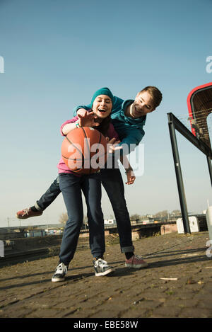 Teenage boy and girl playing basketball outdoors, industrial area, Mannheilm, Germany