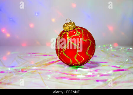 Red Christmas ball on the table with the tinsel on the background lights Stock Photo