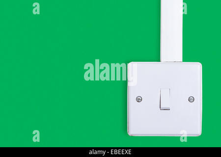 Light switch mounted on green background with copy space. Old square box style switch. Stock Photo