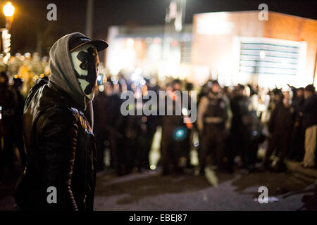 Ferguson, USA. 28th Nov, 2014. A protester in mask looks back as police come in from behind and box in many protesters near the Ferguson PD Station in Ferguson, Missouri, the United States, on Nov. 28, 2014. Police arrested 15 people Friday night as about 100 protesters blocked traffic in front of the local police department in Ferguson. The protest was the latest one in reaction to the non-indictment of police officer Darren Wilson, who shot and killed unarmed 18-year-old black youth Michael Brown in August. © Jim Vondruska/Xinhua/Alamy Live News Stock Photo