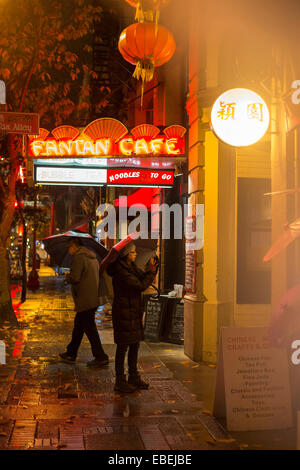 Chinese couple at Fan Tan alley entrance in Chinatown on rainy night-Victoria, British Columbia, Canada. Stock Photo