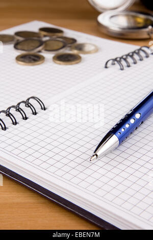 pen and coin on notebook Stock Photo