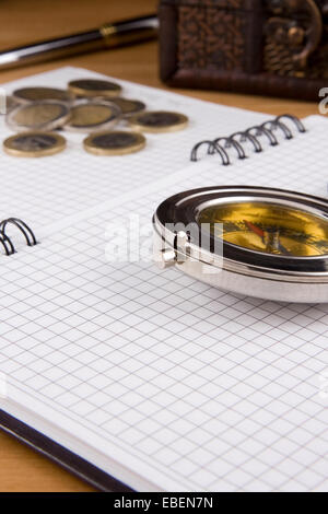 compass, pen and coin on checked notebook Stock Photo