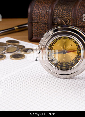 compass, pen and coin on checked notebook Stock Photo