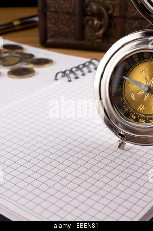 silver compass, gold coin and notebook Stock Photo