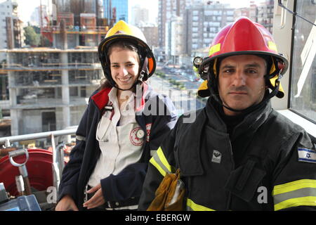 Ramat Gan, Israel. 28th November, 2014. Firefighter and medical aide person wait for injured victims for evacuation while they stand in a basket on top of a crane, during 'Tower Inferno II' fire drill from Israel's tallest highrise. Credit:  Eden Akavia/Alamy Live News Stock Photo