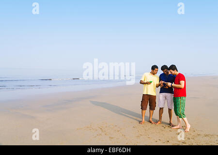indian friends beach  Dialing  Mobile Phone Stock Photo