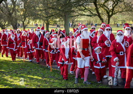 People (men, women & children) dressed in red & white Father Christmas outfits with hats & fake beards, are standing, waiting to start & take part in The Great Skipton Santa Fun Run, an annual fundraising charity race organised by the Rotary Club - Aireville Park, Skipton town centre, North Yorkshire, England, UK. Stock Photo