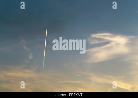 The plane flies low in the sky, leaving a white trail Stock Photo