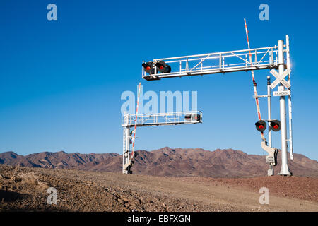 A busy railroad crossing in front of desert mountains Stock Photo