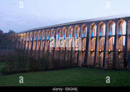 3-second time exposure of a train on a viaduct at twilight. LED lights illuminating the 2nd and 3r floor. Chaumont, Haute-Marne, Grand Est, France. Stock Photo