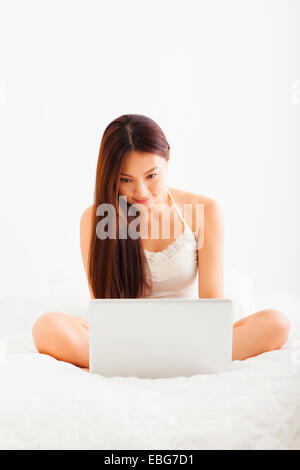 beautiful young asian woman using laptop in bed Stock Photo