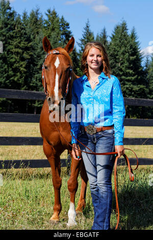 41,857.09269 teenage girl in blue standing by & holding a bay horse Stock Photo