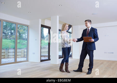 Woman Shaking Hands With Estate Agent In New Home Stock Photo