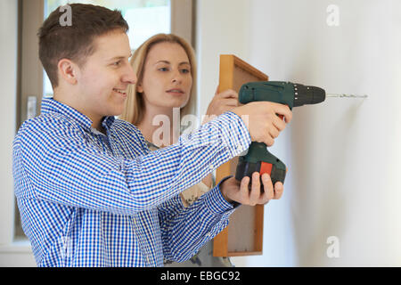 Couple Drilling Wall To Hang Picture Frame Stock Photo