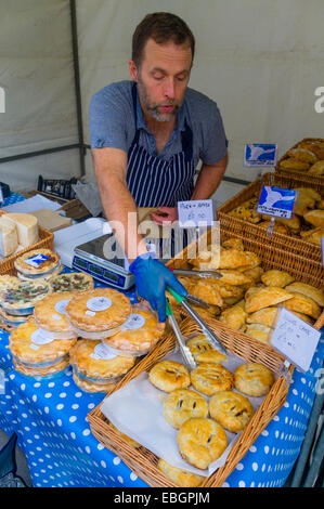 A man selling locally made cakes and pies at Aberystwyth food farmers market Wales UK Stock Photo