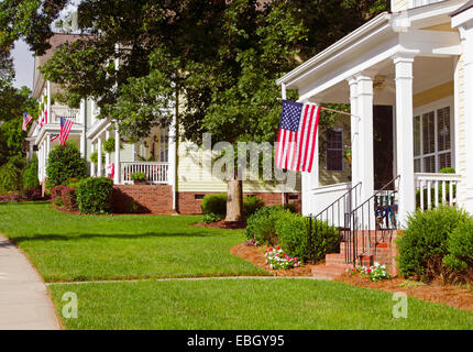 An American Flag hangs from a front porch in a neighborhood of Victorian-style homes in celebration of the upcoming holiday. Stock Photo