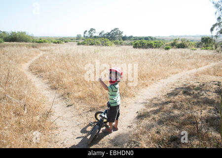 Young boy on path in field with bike Stock Photo